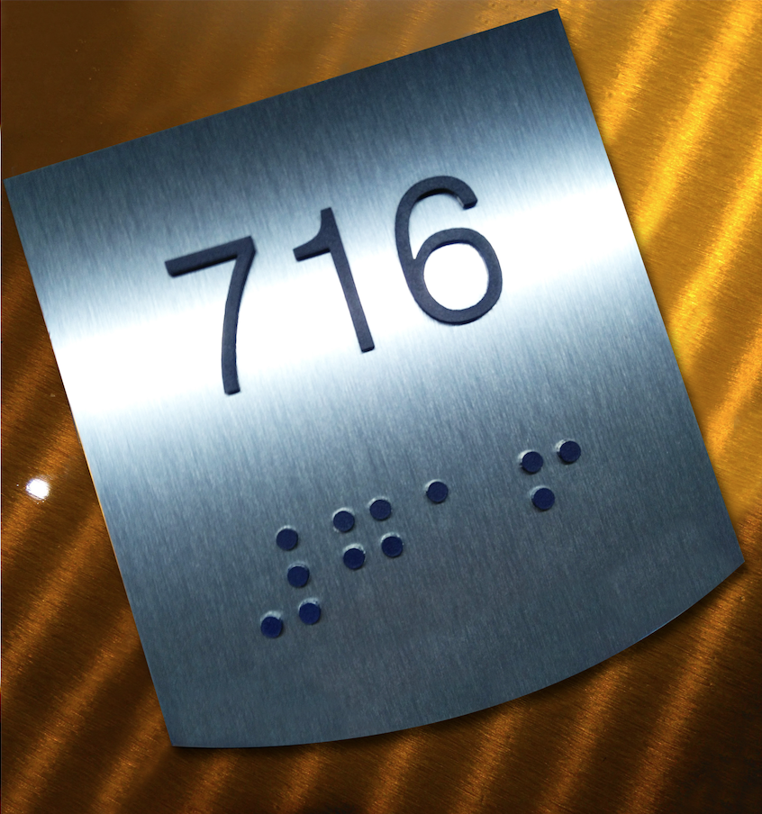 demonstrates metal crafted wayfinding sign with braille