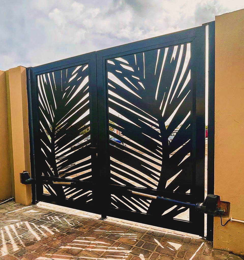 Custom aluminum motorized gate with palm leaf design by Infinite Crafts in Aruba, built for durability and style.